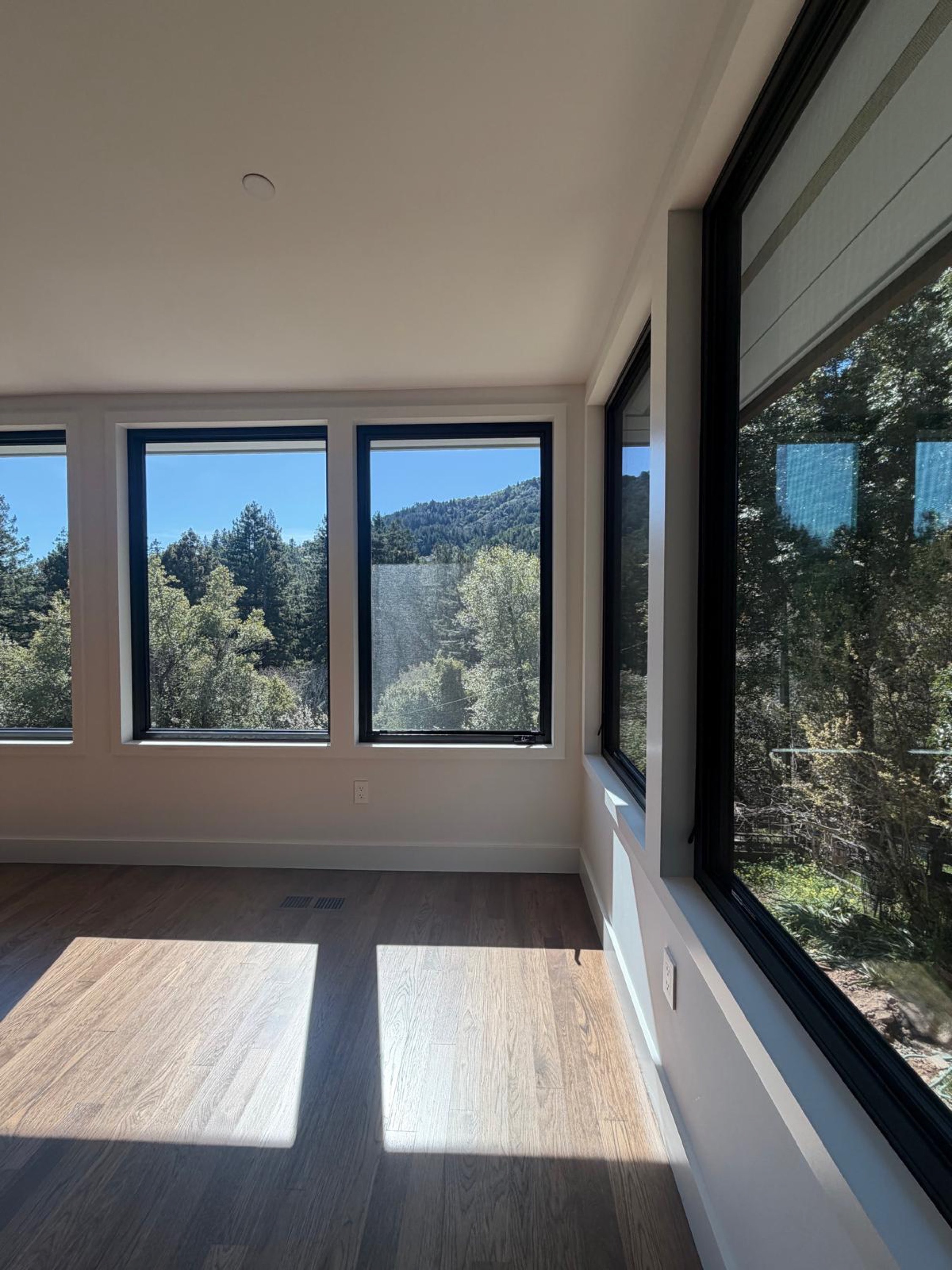 Finished room with new black-frame windows overlooking wooded hills